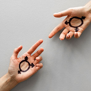Deux mains tendues l'une vers l'autre possédant une marque réprésentant le symbôle transgenre.